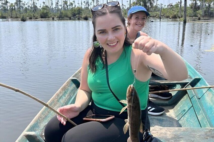 Twee mensen in een boot op een kalm wateroppervlak, met beplanting op de achtergrond. 4