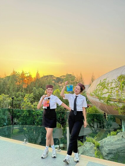Two individuals in uniforms standing by a glass railing with a sunset in the background. 2