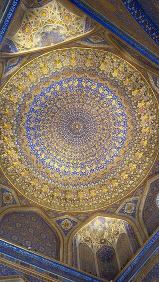 A detailed ceiling with intricate geometric and floral patterns, predominantly in blue and gold. 3