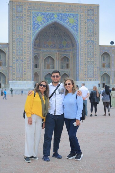 A group of people standing in front of a large, intricately designed building with arched windows and detailed tile work. 1