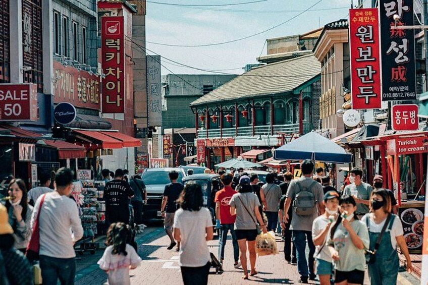 Une rue animée, avec des piétons, des boutiques et une tente bleue. 2
