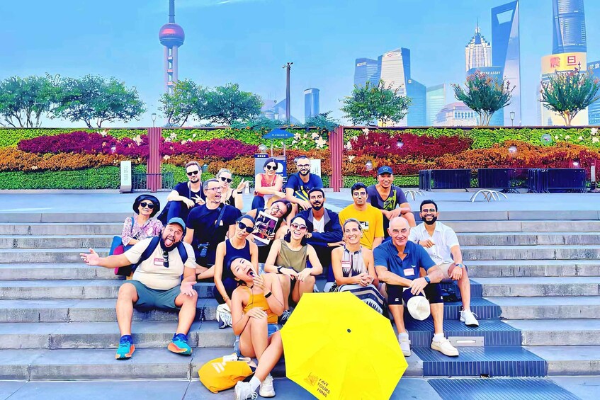 A group of people sitting on steps with a cityscape in the background. 1