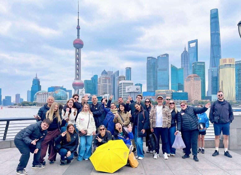 A group of people posing in front of a city skyline with a prominent tower and modern buildings. 2