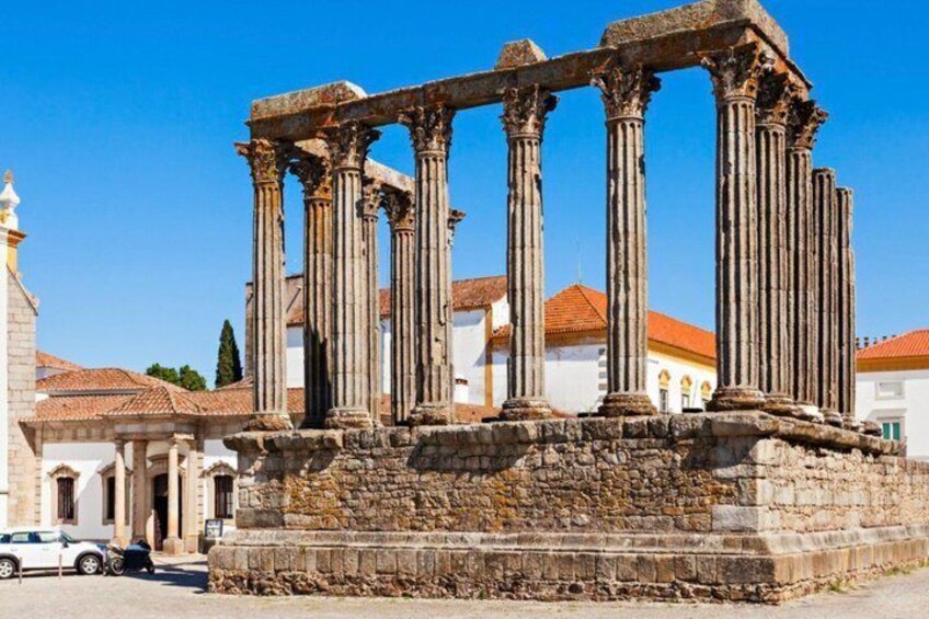 Ancient Roman columns in a historical site with buildings in the background. 1