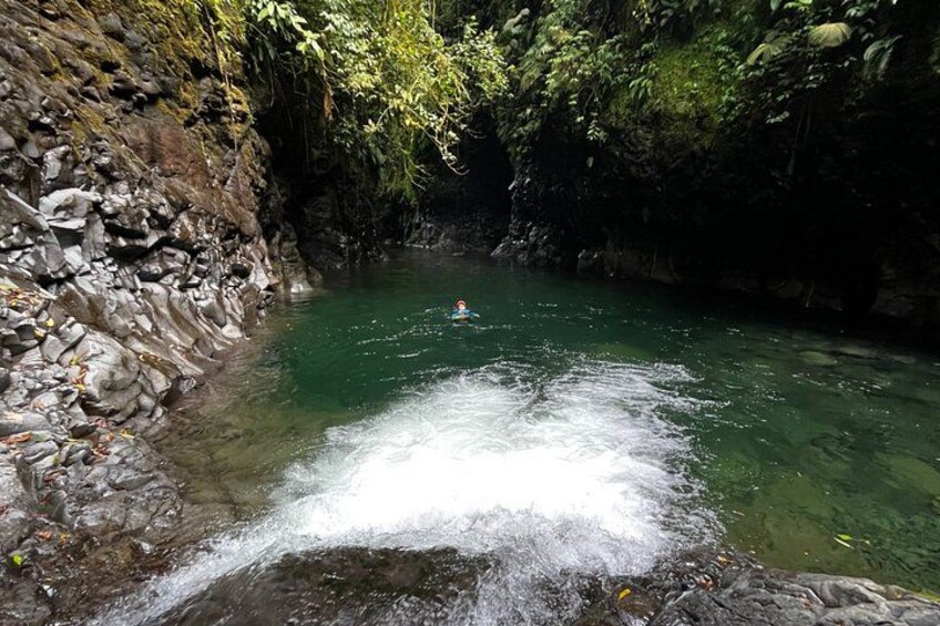 A river with a person kayaking, surrounded by rocky cliffs and dense vegetation. 3