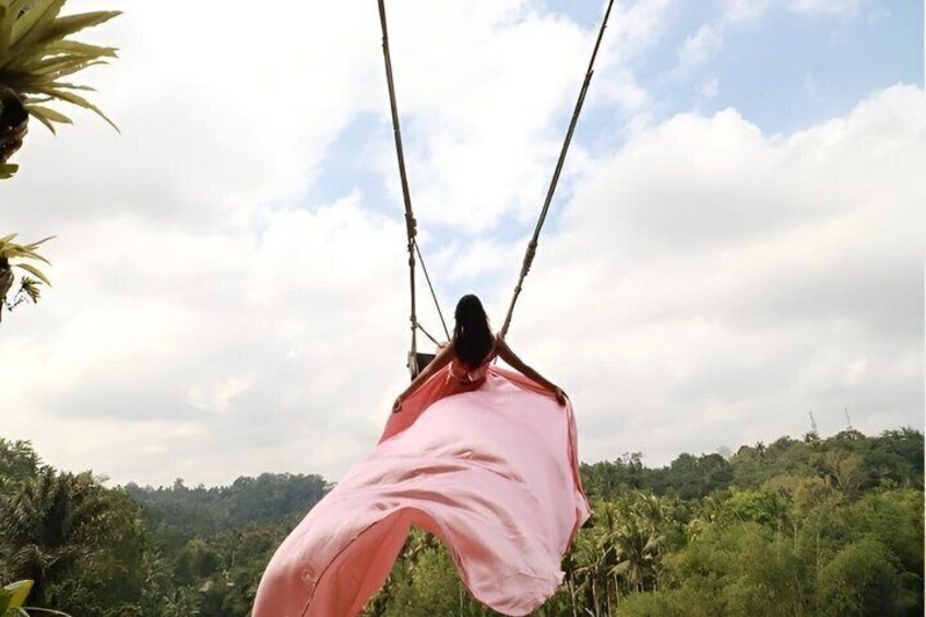 A person swinging on a rope swing over a lush green landscape. 3