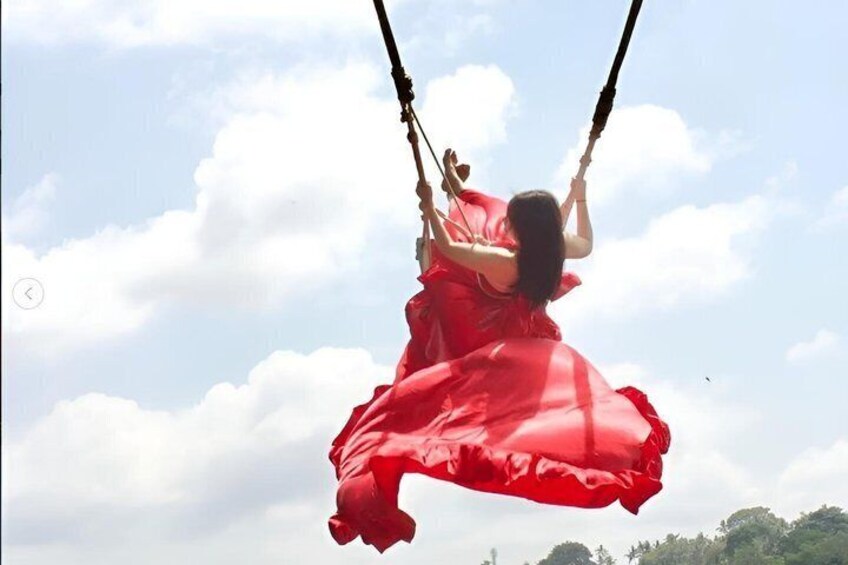 A person in a red dress swinging on a swing. 4