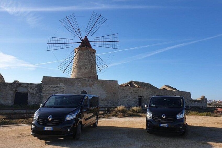 Twee auto's geparkeerd voor een windmolen en een stenen gebouw. 4