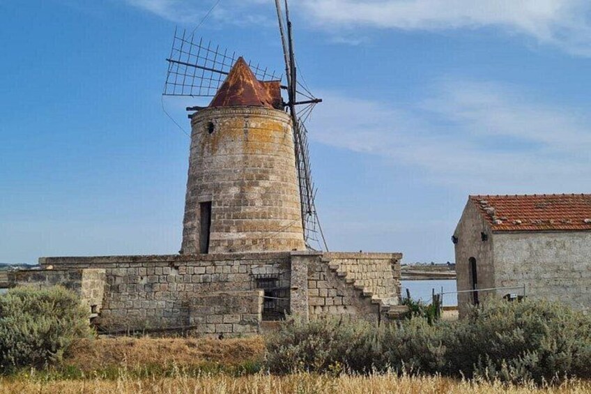 Een windmolen met een metalen spijlenstructuur, een stenen fundering en een dak van rode dakpannen. 2