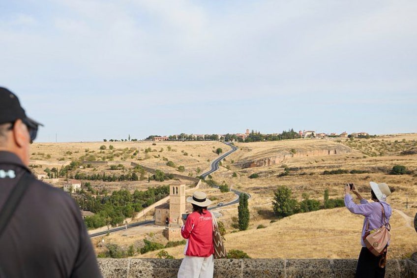 Paesaggio con una strada tortuosa, una chiesa e due persone che scattano fotografie. 3