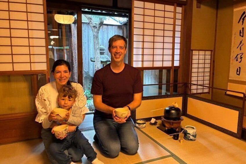 En familie i et traditionelt japansk rum med tatamimåtter, skydedøre og et te-stel. 4