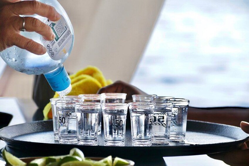 En person som häller vatten i små glas på ett bricka. 5