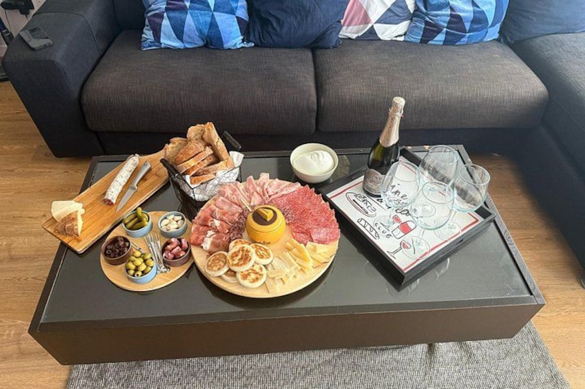 A charcuterie board with various meats, cheeses, and fruits on a coffee table. 2