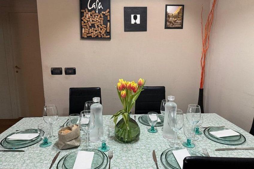 A dining table set with glassware, plates, and a vase of tulips. 3