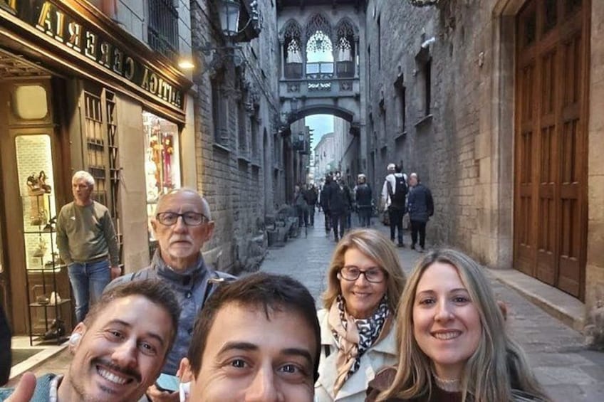 A narrow street with historic buildings, a shop with a sign, and people walking. 1