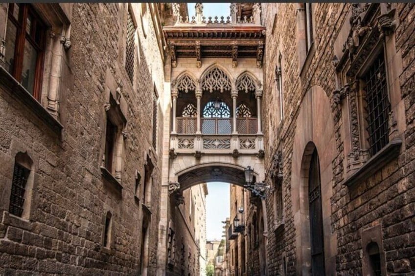 Una estrecha calle medieval con edificios de piedra, un arco decorativo y un pequeño balcón con detalles intrincados. 5