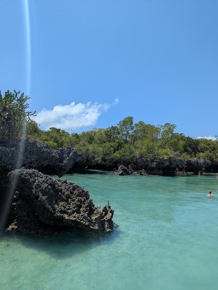 Ein klares türkisfarbenes Meer, Felsformationen und dichtes Grün unter blauem Himmel. 4