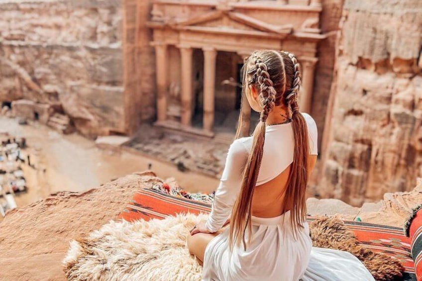 Une personne assise sur un tapis en fourrure devant un grand temple antique. 5