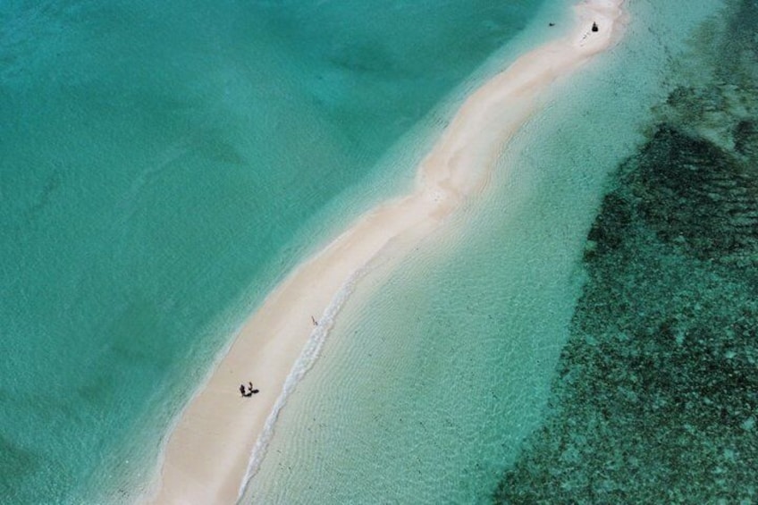 Una spiaggia sabbiosa con acqua cristallina color turchese, una stretta fascia di vegetazione e una piccola barca. 5