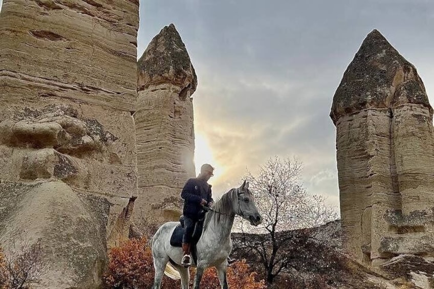 A person riding a horse in front of rock formations. 1