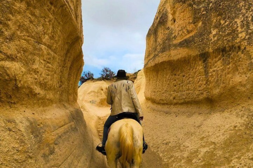 A person riding a horse through a narrow canyon. 4