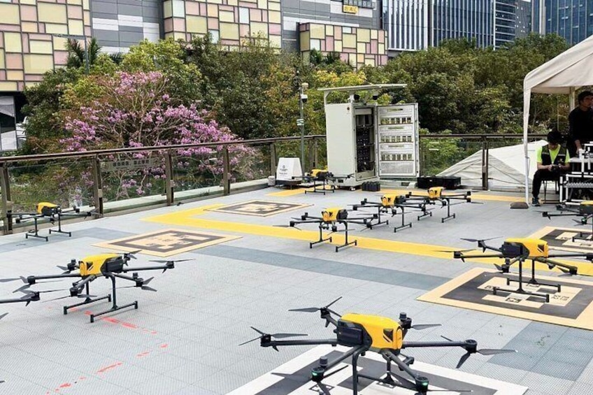 Una azotea con varios drones sobre esteras de aterrizaje, una estación de control y una carpa blanca. 1