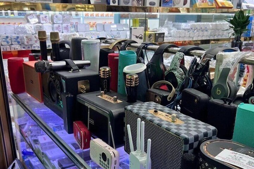 En udstilling af forskellige elektroniske apparater, herunder højttalere, hovedtelefoner og en mobiltelefon, i en butik. 5
