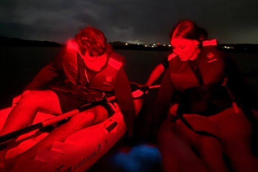 Two people sitting on a boat at night with a red light. 2