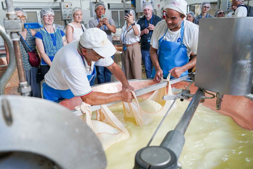 A cheese-making process with workers and onlookers in a factory setting. 5