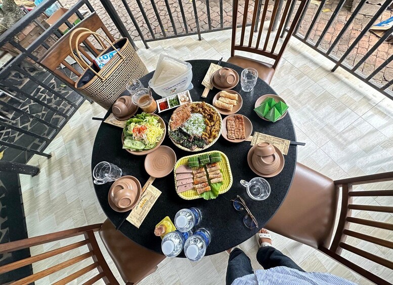 A round table with various dishes, drinks, and a handbag. 3