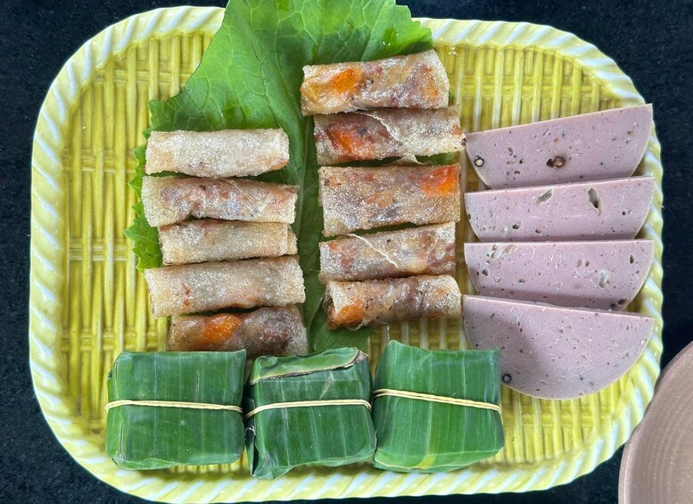 A plate with spring rolls, sliced meat, and tamales. 2