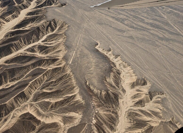 A rugged desert landscape with deep canyons and a straight road cutting through it. 4