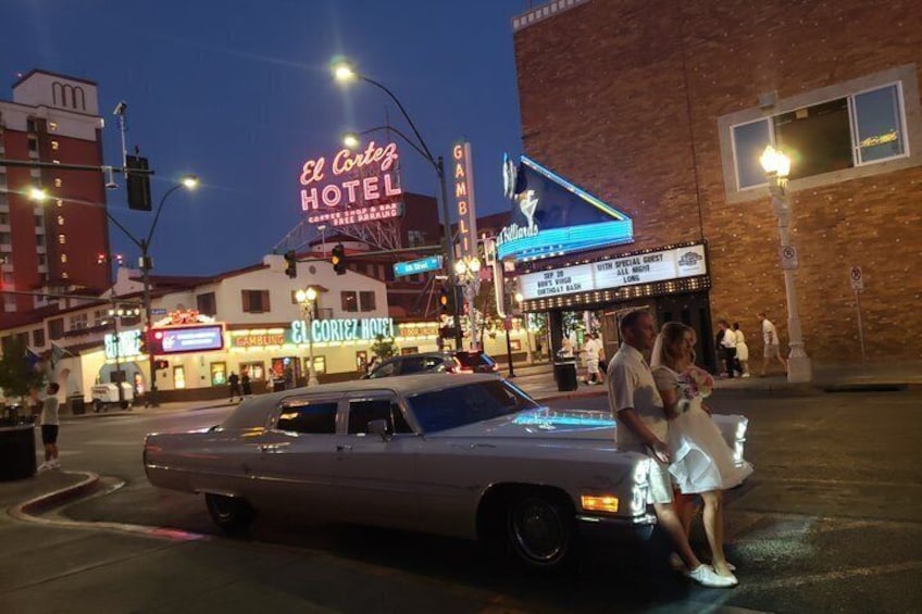 Une voiture ancienne est garée à un coin de rue, avec des enseignes au néon indiquant l’hôtel El Cortez et un cinéma en arrière-plan. 4