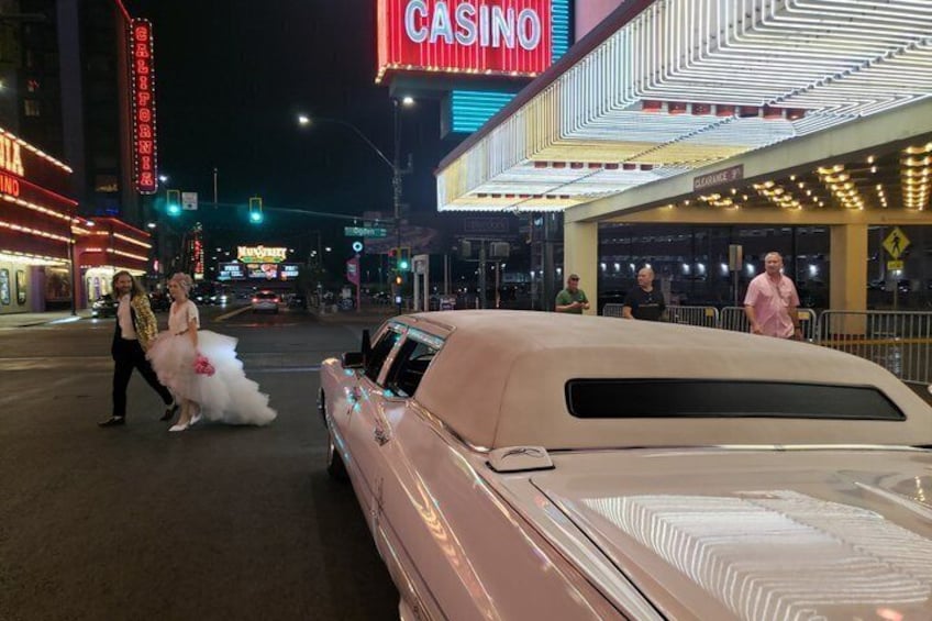 Une voiture ancienne garée dans une rue de la ville, avec des enseignes lumineuses de casino en arrière-plan. 5