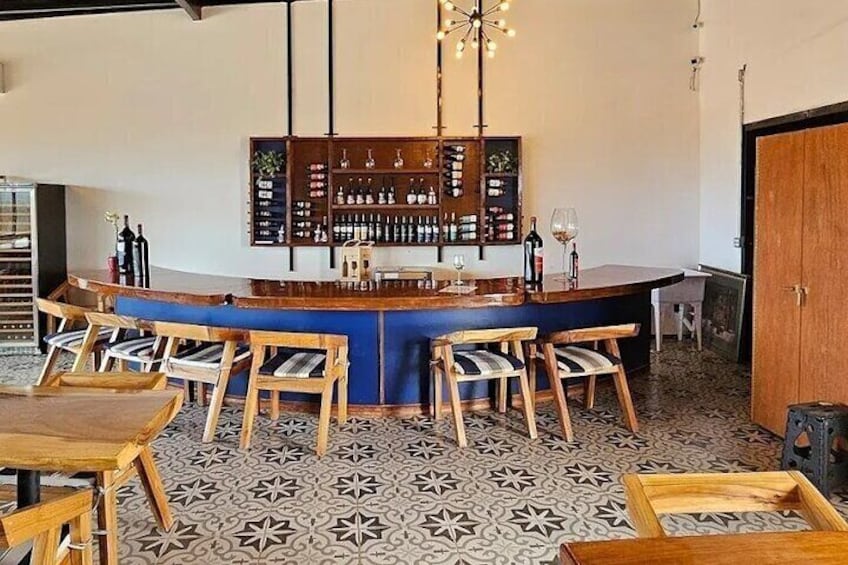 Un bar avec un comptoir bleu, des chaises en bois et un sol à motifs. 2
