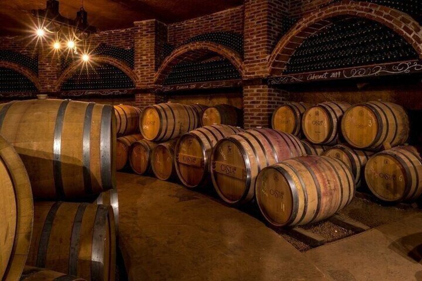 Des barriques en bois, empilées dans une cave aux murs de briques et aux plafonds voûtés. 5