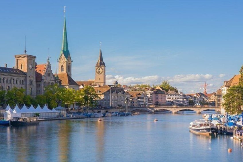 A river with boats, a bridge, and historic buildings including a church with a green spire. 2