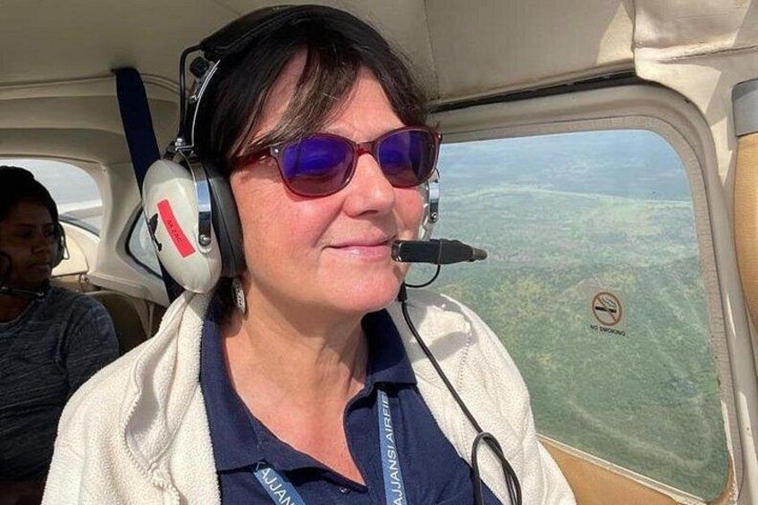 A person wearing a headset and a white jacket inside an aircraft. 5