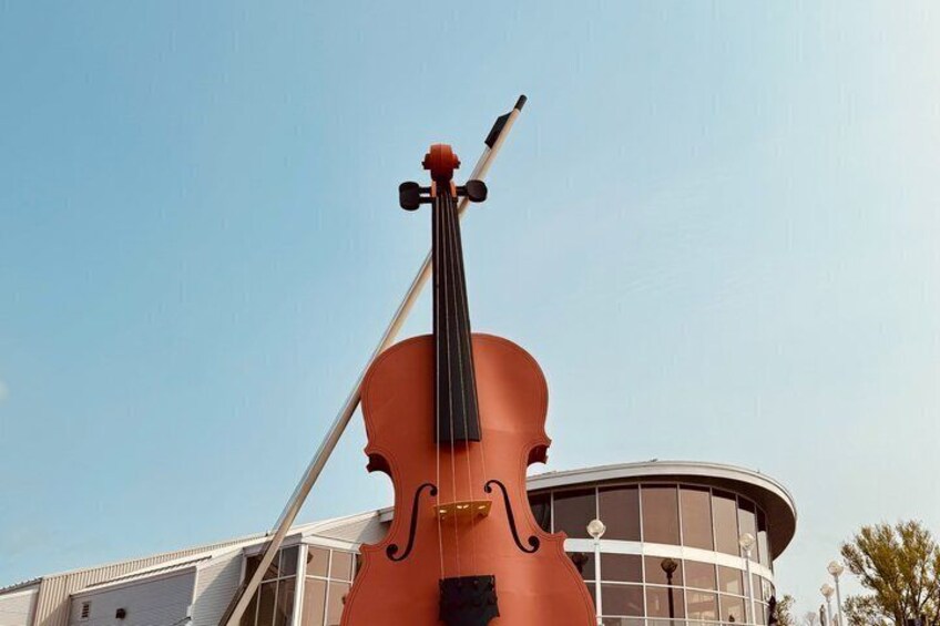 A large violin sculpture in front of a building. 4