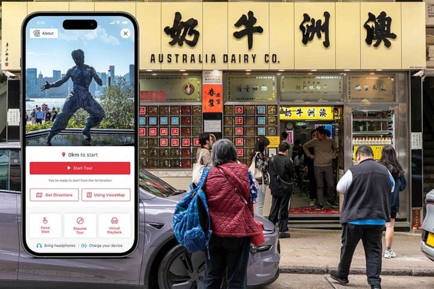 Un smartphone affiche une carte avec le message « 9 km avant le départ », une personne portant une veste rouge, et la devanture d’un magasin avec des caractères chinois et une enseigne indiquant « AUSTRALIA DAIRY CO. ». 1