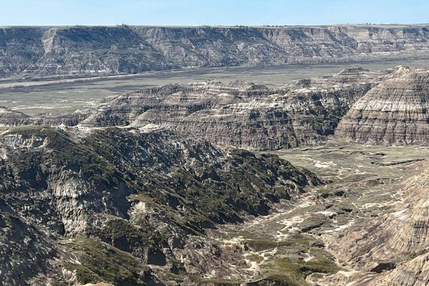 A vast landscape with layered rock formations and sparse vegetation. 3