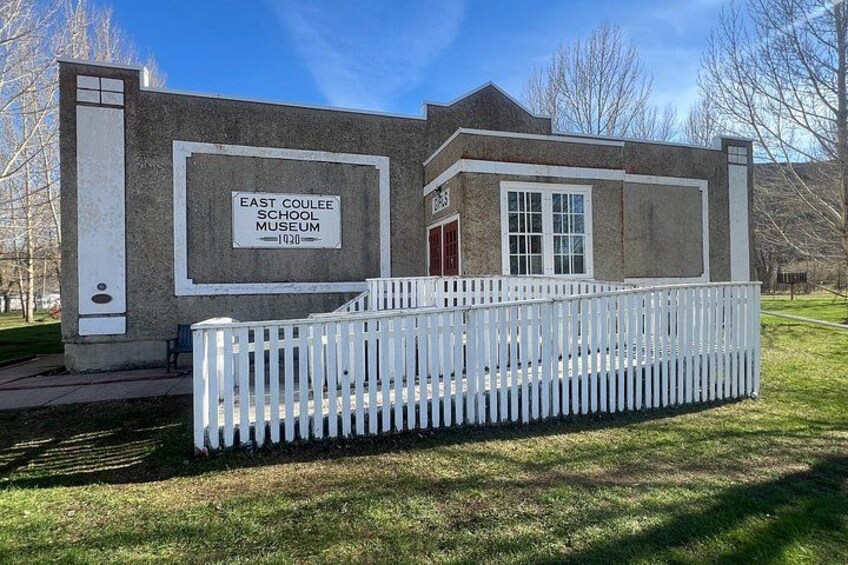 A building labeled as East Coulee School Museum with a white picket fence in front. 2