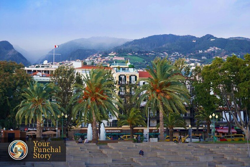 A coastal town with palm trees, a church, and a view of the mountains. 2