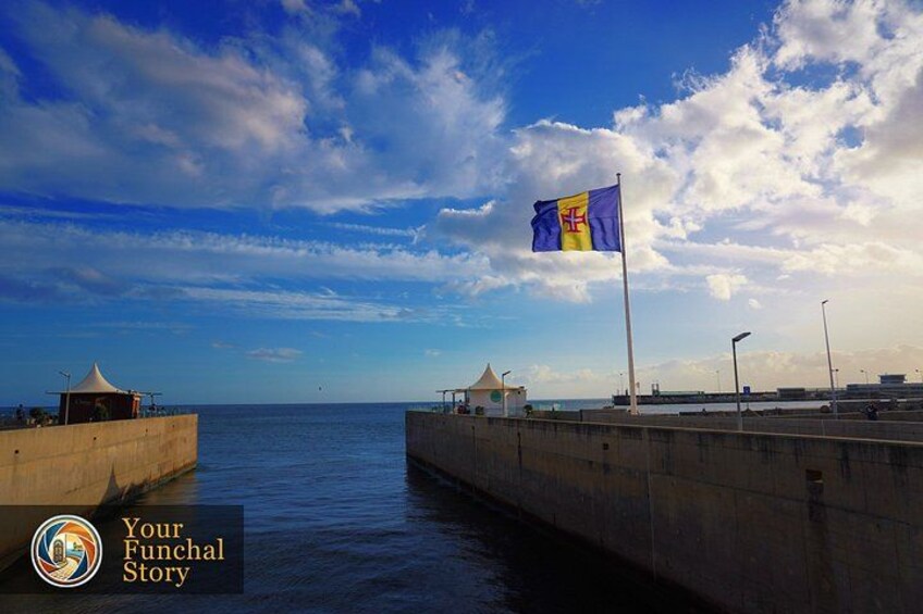 A coastal scene with a flag, a pier, and a clear sky. 5
