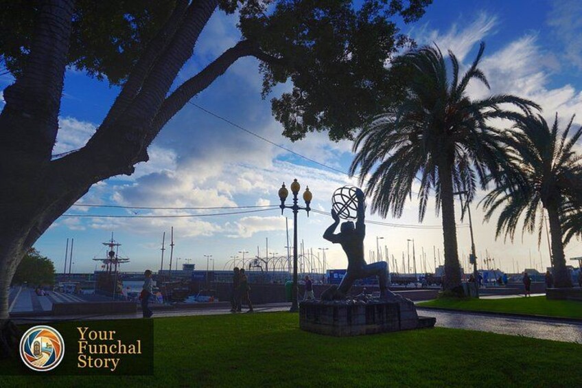 A park with a statue, palm trees, and a waterfront with boats. 3