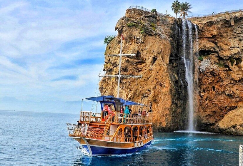 A boat with passengers near a cliff with a waterfall. 4