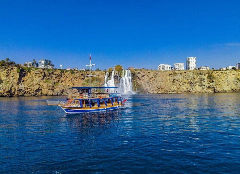 A boat named 'Atlantic' on calm waters with a waterfall in the background. 2