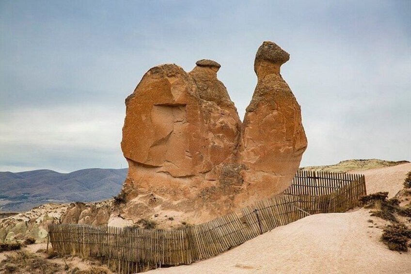 A large rock formation with a wooden fence in the foreground. 5