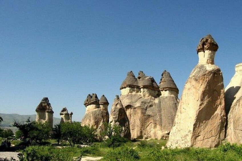 A landscape with prominent rock formations resembling mushrooms, a clear sky, and sparse vegetation. 4