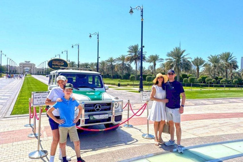 A green Mercedes-Benz S-Class SUV parked on a paved area with palm trees and a clear sky in the background. 2
